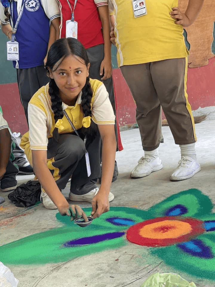 A student creating rangoli during a school cultural activity